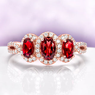 Three Stone Garnet Engagement Ring in 14K Rose Gold Vermeil by Aquamarise with three oval garnets and sparkling diamond accents in an elegant rose gold setting.