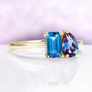 Gold ring with blue and purple gemstones on a white background