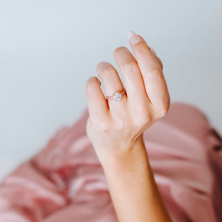 Hand with a diamond ring on a pink and white background