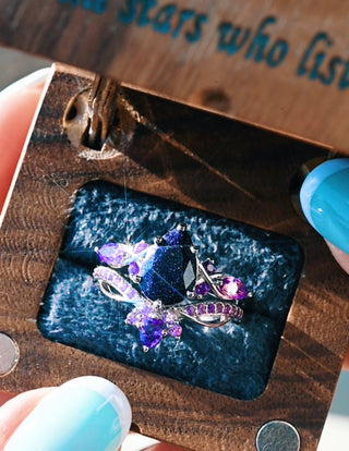 Jewelry box with a ring featuring purple gemstones on a blue stone
