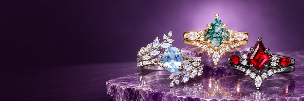 Aquamarine moonstone leaf ring, kite moss agate yellow gold ring and kite ruby black rhodium ring on an amethyst slab