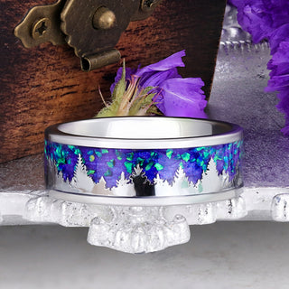 Borealis Forest 8mm tungsten men's band with silver pine tree silhouettes against a purple and green opal sky, displayed on a silver stand