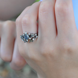 Close-up of the Carmilla gray moissanite and black onyx ring in black ruthenium on the finger