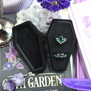 Angled view of the black velvet coffin ring box and its lift-off lid with two rings inside