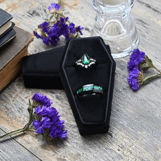 Black coffin double ring box on weathered wood with old books and purple flowers