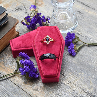 Red coffin double ring box on weathered wood with old books and purple flowers