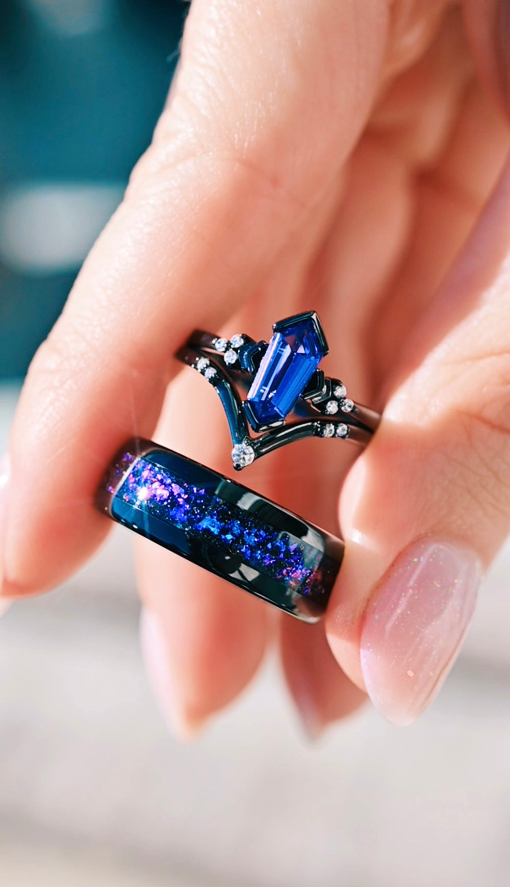 A hand holding a matching couples ring set
