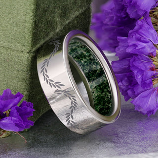 Polished titanium men's band with engraved leaf vine and crushed moss agate lining the inside, styled with purple flowers