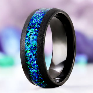 Crushed Peacock Opal men's wedding band in sandblasted black tungsten, 8mm, standing upright with the blue-green peacock opal inlay