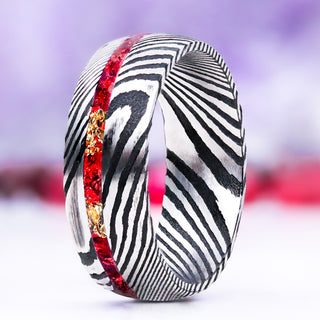 Crushed Red Garnet & Gold Leaf men's wedding band in domed Damascus steel, 8mm, standing upright with the red garnet and gold leaf channel running through the black-and-silver Damascus pattern