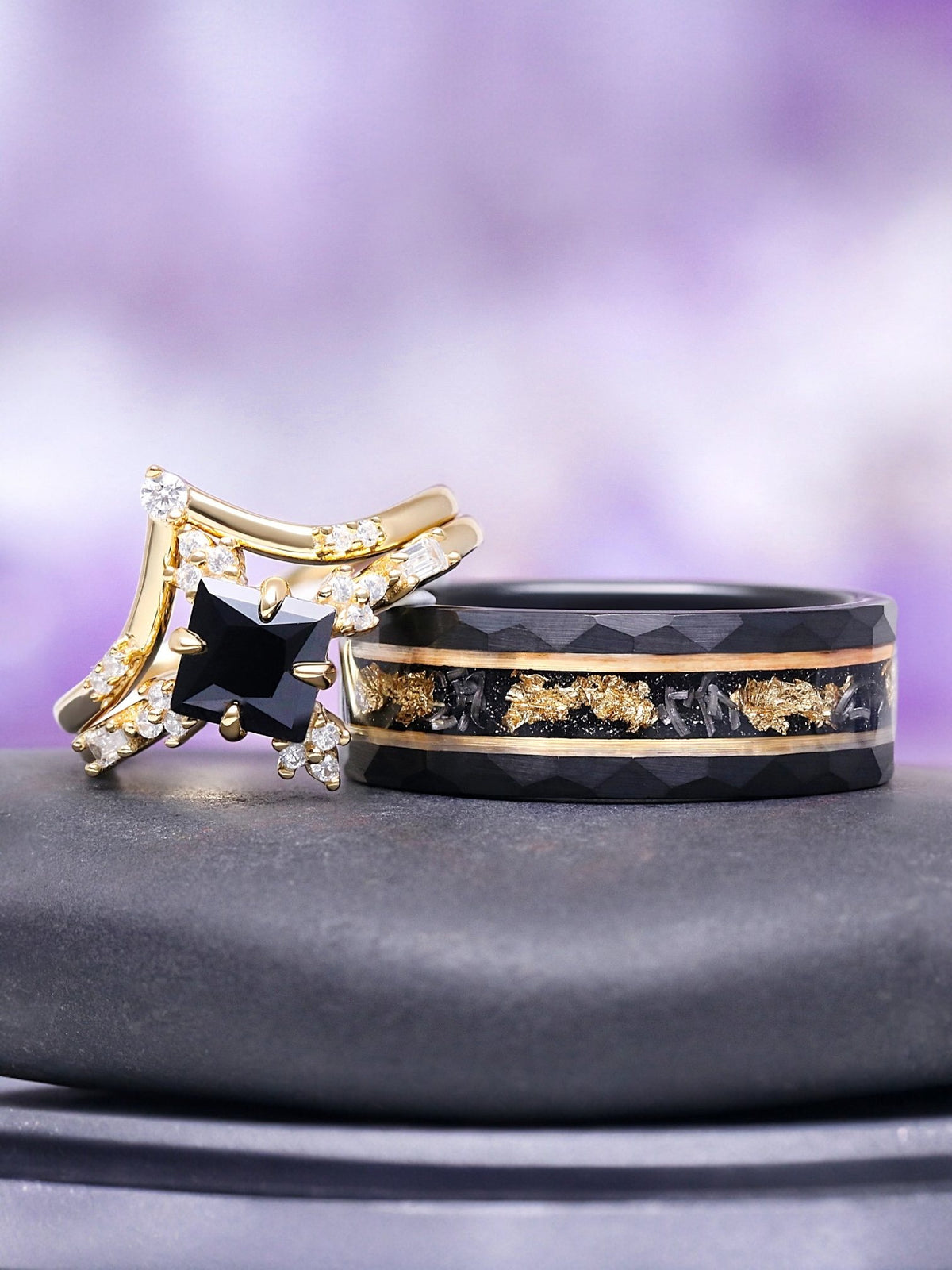 Dark Romance couples ring set by Aquamarise – a yellow gold princess-cut black onyx engagement ring with a curved band beside a men's black band with gold leaf inlay