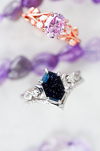 Two rings with gemstones on a soft purple fabric background