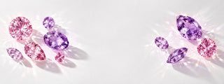 Loose pink and purple gemstones in round, oval, pear and marquise cuts casting light on a white surface, Aquamarise Ethical Sourcing page banner