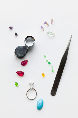 Jewelry-making tools and gemstones on a white background