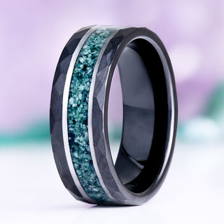 Green Moss Agate hammered men's wedding band in black and silver tungsten standing upright, showing the crushed moss agate inlay between silver rails