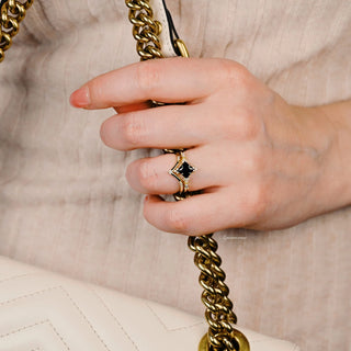 Black Onyx & Meteorite Gold Leaf Couples Ring Set worn on hand holding gold chain strap of cream leather bag, showcasing black gemstone and elegant gold leaf design by Aquamarise.