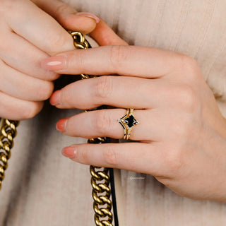 Black Onyx & Meteorite Gold Leaf Couples Ring Set featuring a gold band with black onyx and meteorite details, styled on a hand holding a gold chain, by Aquamarise.