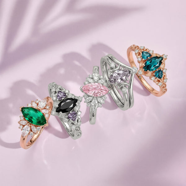 Five jewelry rings with various gemstones on a pink fabric background