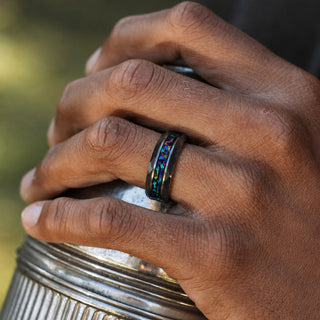 Man wearing the 8mm Mystic Topaz & Galaxy Opal men's wedding band in tungsten carbide, black band with a multicolour crushed galaxy opal inlay
