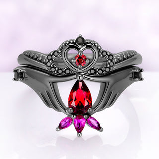 Natural Garnet & Lab-Grown Ruby Claddagh Engagement Ring Set in Black Ruthenium by Aquamarise, two hands holding a pear garnet with the heart and crown band nested above