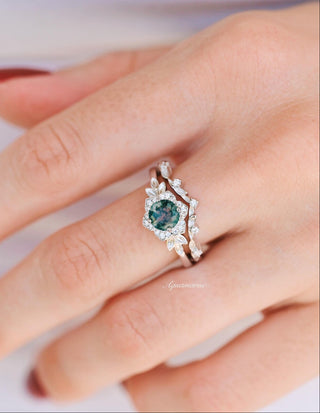 Close-up of a hand wearing a ring with a green gemstone on a white background