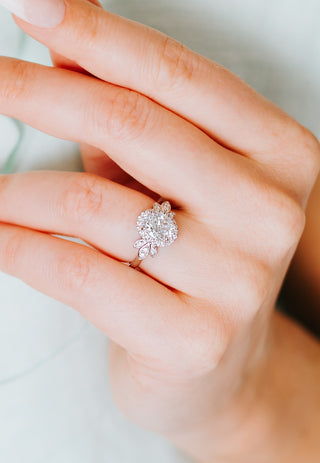 Close-up of a hand wearing a diamond ring on a neutral background