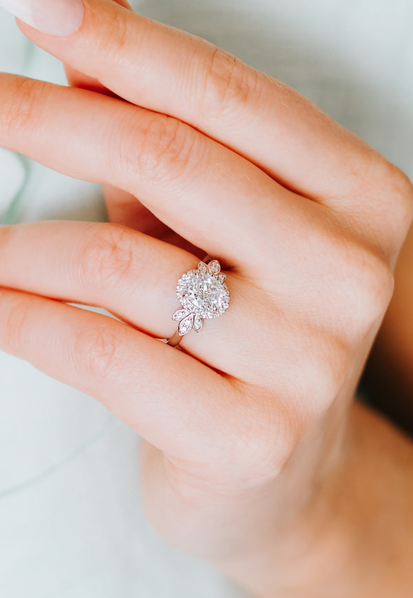 Close-up of a hand wearing a diamond ring on a neutral background