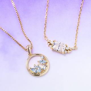 Two gold necklaces with gemstones on a light purple background