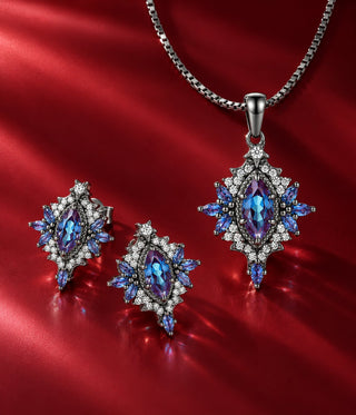 Night Briar jewelry set in black rhodium on red satin: marquise halo stud earrings and matching pendant necklace with blue-violet color-change center stones and blue marquise accents, Aquamarise banner