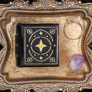 Night Court leather book ring box by Aquamarise in black and gold, opened to reveal the ring slot