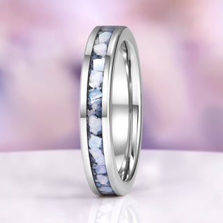 Silver ring with embedded stones on a blurred purple and pink background