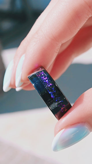 Hand holding black onyx galaxy ring space inspired wedding band
