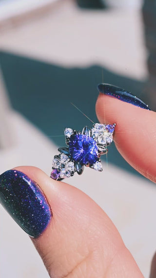 Video of the Noraleaf Lab-Grown Purple Sapphire Engagement Ring in Black Ruthenium by Aquamarise held in sunlight, purple center stone with leaf-shaped accents