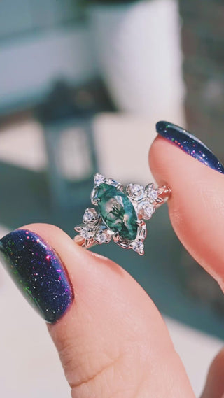 Video of the Viridian Marquise Moss Agate Engagement Ring by Aquamarise held in sunlight, showing the green moss agate center and marquise accent stones