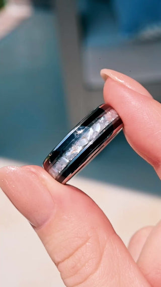 Video of the Black Onyx & Pearl Men's Wedding Band in Tungsten Carbide (8mm) by Aquamarise held outdoors, showing the crushed pearl inlay between black onyx edges