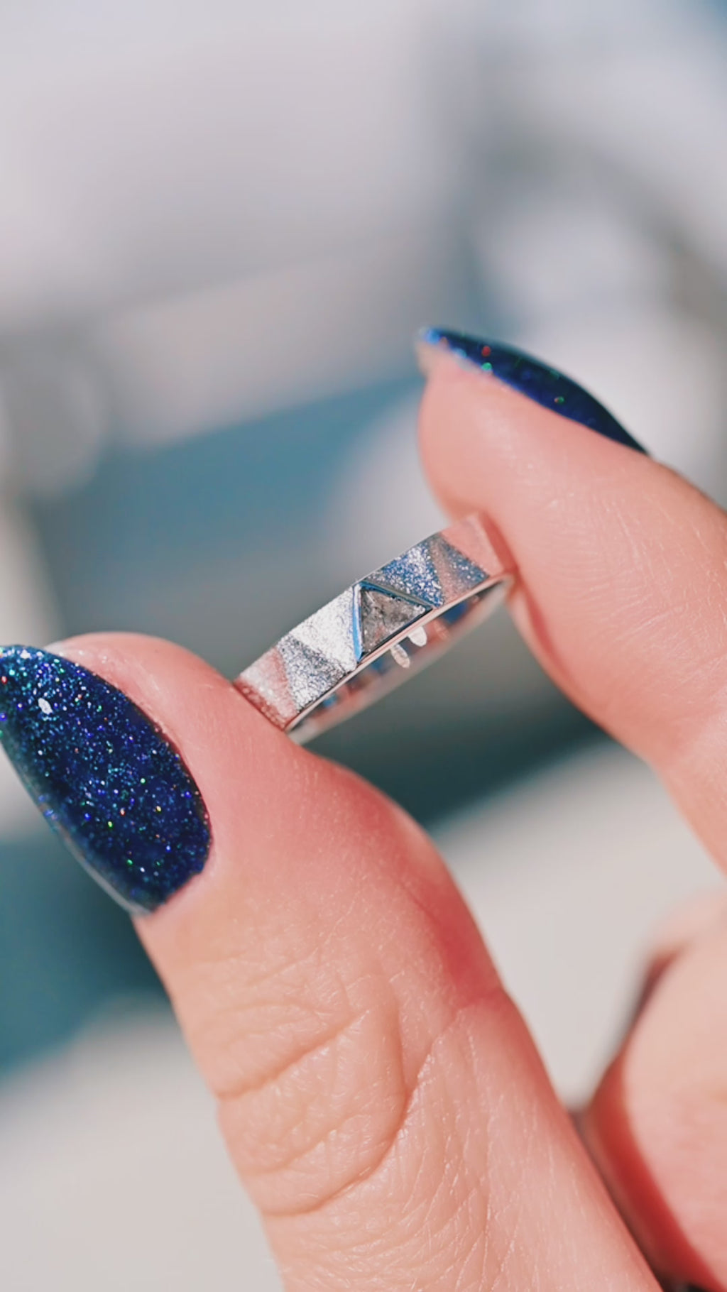 silver rings with geometric designs on a gray surface with a purple gradient background