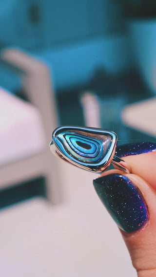 Video of the Abalone Paua Shell Ring in Sterling Silver by Aquamarise held in sunlight, showing the blue and teal bands of the shell