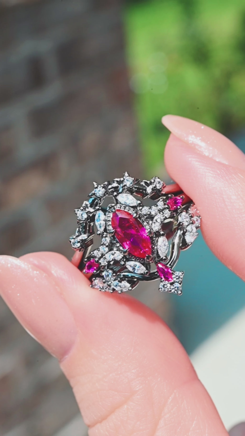 Nightbriar lab-grown ruby bridal ring set in black ruthenium held close, showing the marquise ruby center and pave leaf detailing