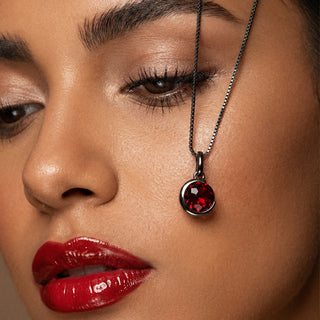 Close-up of a woman's face wearing a necklace with a red pendant.