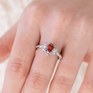 Silver ring with a red gemstone on a person's finger