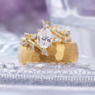 Close-up of the gold leaf and vine engagement ring with oval center stone stacked on the brushed hammered gold band