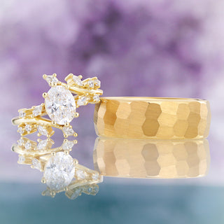 Side by side view of the oval simulated diamond leaf ring and faceted hammered yellow gold men's wedding band