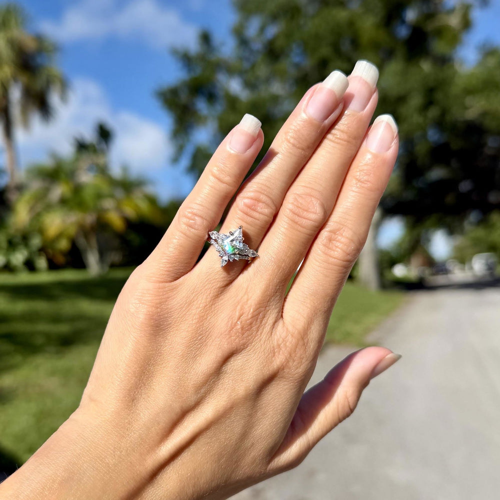 Hand held up under palm trees and blue sky wearing the Skye Kite® simulated diamond bridal ring set in sterling silver – Aquamarise customer photo