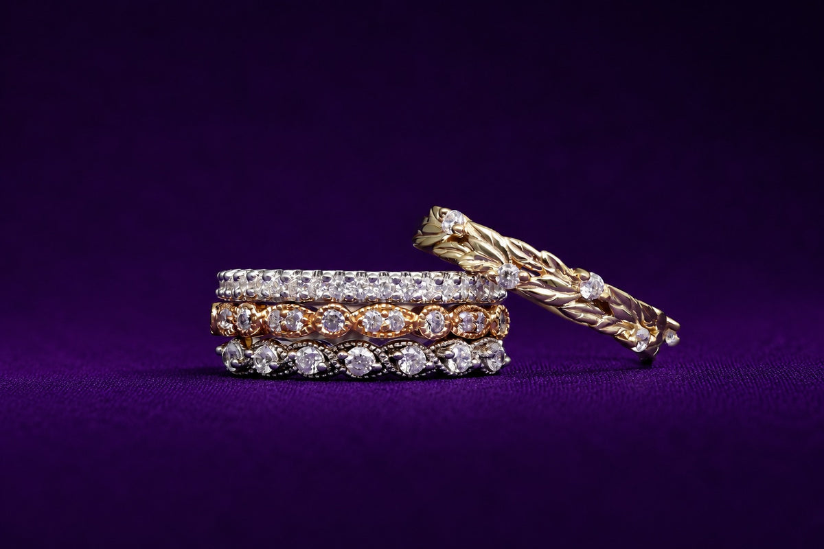 Three stacked pave eternity bands in sterling silver, rose gold and yellow gold with a yellow gold leaf vine band on purple velvet, Aquamarise wedding band collection banner