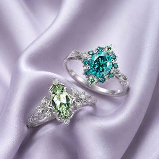 Two sterling silver rings on lilac satin, a teal round halo ring and a green marquise leaf ring, Aquamarise collection banner