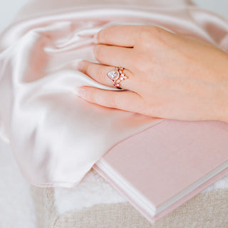 Hand wearing a ring on pink fabric