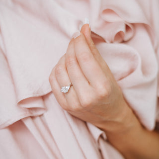 Hand wearing a diamond ring on pink fabric