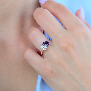 Close-up of the pear alexandrite and emerald cut toi et moi ring on the finger