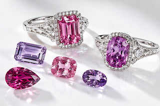 Two white gold halo rings with a pink emerald-cut sapphire and a purple cushion sapphire beside loose pink and purple gemstones on white, Aquamarise Transparency page mobile banner