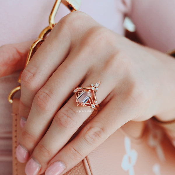 Rose gold ring with a large central gemstone on a hand against a pink background